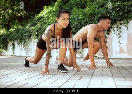 Eine muskulöse Athleten, Training im Park. Gymnastik, Training, Fitness Workout Flexibilität. Sommer Stadt im sonnigen Tag auf Hintergrund Feld. Aktiven und gesunden Lebensstil, Jugend, Bodybuilding. Stockfoto