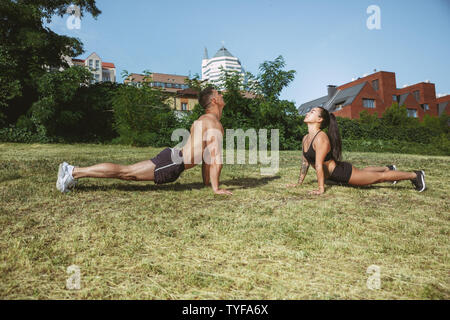 Eine muskulöse Athleten, Training im Park. Gymnastik, Training, Fitness Workout Flexibilität. Sommer Stadt im sonnigen Tag auf Hintergrund Feld. Aktiven und gesunden Lebensstil, Jugend, Bodybuilding. Stockfoto