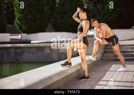 Eine muskulöse Athleten, Training im Park. Gymnastik, Training, Fitness Workout Flexibilität. Sommer Stadt im sonnigen Tag auf Hintergrund Feld. Aktiven und gesunden Lebensstil, Jugend, Bodybuilding. Stockfoto