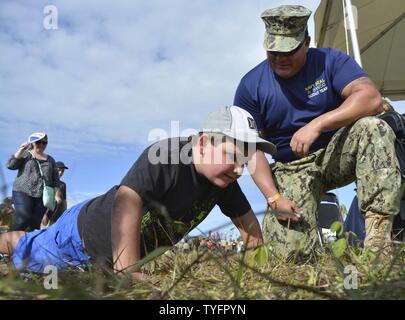 STUART, Fla (Nov. 6, 2016) - Chief Petty Officer Joseph Schmidt, die Navy SEAL und SWCC Scout Team zugewiesen, fördert ein junger Fan pushups an den 2016 Stuart AirShow zu tun. Die Scout Team betreibt Öffentlichkeitsarbeit für kommunale Gruppen und athletische Mannschaften über die Naval Special Warfare Training Mission zu informieren. Stockfoto