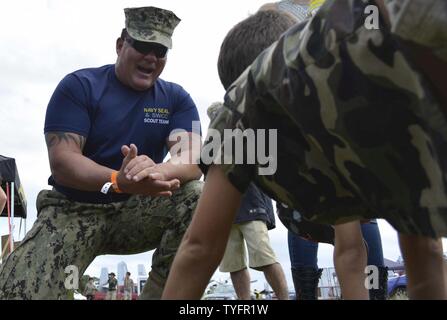 STUART, Fla (Nov. 6, 2016) - Chief Petty Officer Joseph Schmidt, die Navy SEAL und SWCC Scout Team zugewiesen, fördert ein junger Fan pushups an den 2016 Stuart AirShow zu tun. Die Scout Team betreibt Öffentlichkeitsarbeit für kommunale Gruppen und athletische Mannschaften über die Naval Special Warfare Training Mission zu informieren. Stockfoto