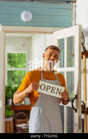 Freundliche Mann mit einer Schürze vor seinem Laden. Stockfoto