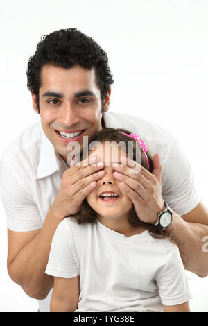 Porträt eines Mannes, der die Augen seiner Tochter von hinten bedeckt Stockfoto