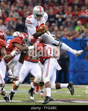 Ohio State quarterback Cardale Jones (12) springt über Alabama Verteidiger Nick Perry (27) und Geno Smith (24) für 18 Yards und einen ersten Abstieg in der ersten Hälfte der Allstate Sugar Bowl Endspiel Halbfinale College Football Spiel im Mercedes-Benz Superdome in New Orleans, Louisiana, am 1. Januar 2015. Foto von David Tulis/UPI Stockfoto