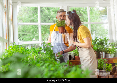 Lächelnd Floristen sniffing Pflanzen zusammen zu arbeiten. Stockfoto