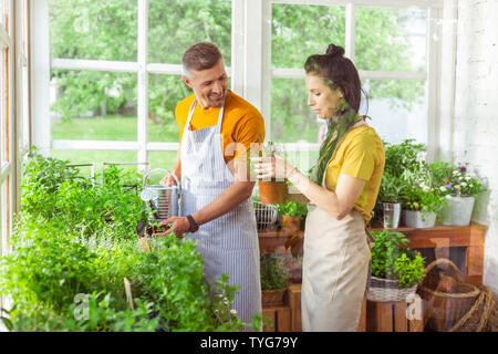 Zwei lächelnde Floristen auf der Suche nach Pflanzen zusammen. Stockfoto