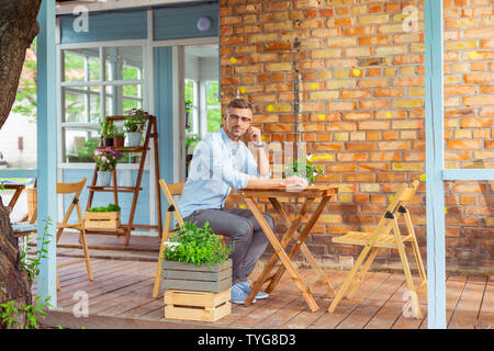 Nachdenklicher Mann, der in einem Sommer Cafe sitzen. Stockfoto