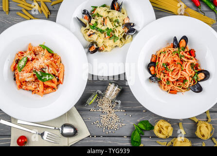 Mittagessen im mediterranen Stil. Spaghetti mit Miesmuscheln in Dosen und Tomatensauce. Auf einem Holztisch, Ansicht von oben. Flach Stockfoto