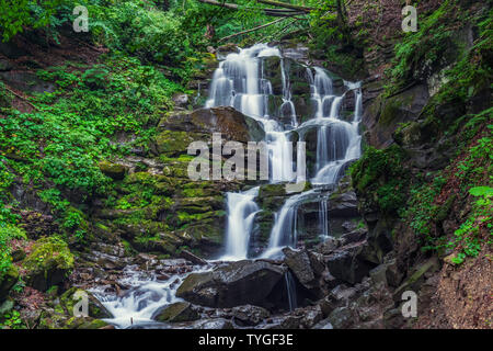 Schönen hohen Wasserfall tief in die Karpaten. Ströme von Wasser, nasse Steine mit grünem Gras und Motte Stockfoto