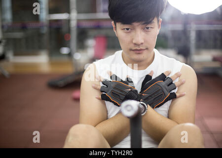 Die Jungen gut aussehenden asiatischer Mann arbeitet in modernen gynm Stockfoto