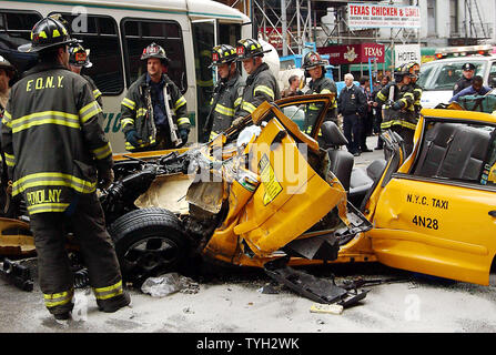 Feuerwehrleute stehen in der Nähe der Überreste eines Taxi am 25. April 2005, die in der Fußgängerzone Fahrerflucht und Kollision mit drei anderen Taxis und einen kleinen Bus, der linken acht auf der West 42nd Street in New York City Verletzten beteiligt war. (UPI Foto/Ezio Petersen) Stockfoto