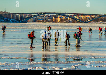 Eine Gruppe von schlittschuhläufer auf den Riddarfjärd, einer Bucht des Sees Malaren, mit dem Vasterbron West Bridge hinter sich. Stockholm, Schweden. Januar 2019. Stockfoto