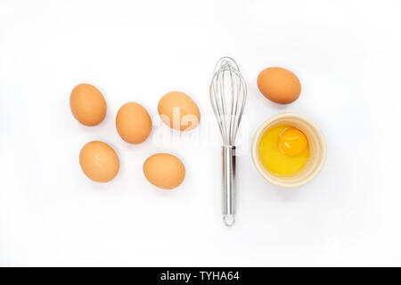 Eier, ein schneebesen und ein Eigelb auf weißem Hintergrund Stockfoto