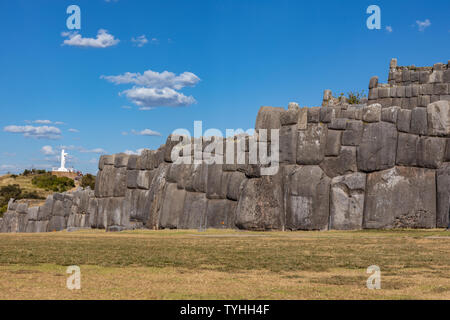 Blick auf die Wand auf der Inca Sacsayhuaman archäologische Stätte und die Statue von Christus symbolisieren Kolonialherrschaft in der Nähe von Cusco, Peru Stockfoto