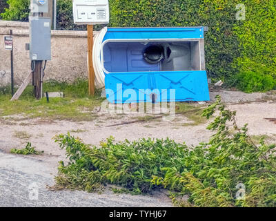 Einen tragbaren Outdoor wc ruht auf seiner Seite, nachdem sie während eines Hurrikans Sturm, die auch unten riss Äste in Florida, USA geblasen. Die meisten mobilen Toiletten sind eigenständige Formstoff- schränke, die sanitären Bedürfnisse von einer Person zu einem Zeitpunkt dienen und werden häufig auf den Baustellen und im Freien öffentlichen Veranstaltungen erforderlich. Während grundlegende Modelle haben nur einen Sitz über der Kloschüssel, und manchmal ein Urinal, deluxe-Modelle verfügen über einen Flush Toilette, Waschbecken, Spiegel, Seife, Toilettenpapier und einem inneren Licht. Einige werden gebaut, die Behinderten gerecht zu werden. Stockfoto