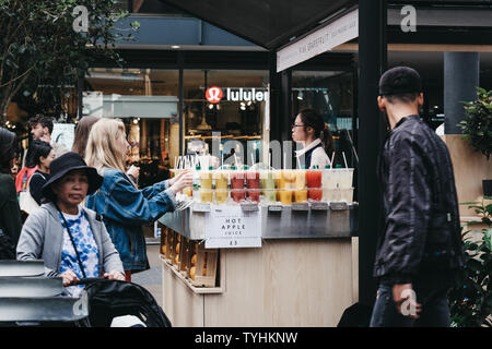 London, UK, 15. Juni 2019: Menschen kaufen frischen Saft in Spitalfields Market, einem der schönsten erhaltenen viktorianischen Markthallen in London mit Verkaufsständen Stockfoto