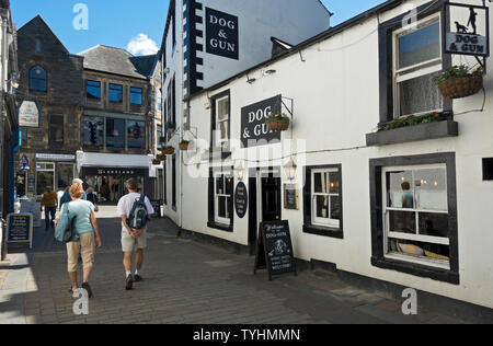 Besucher Touristen, die im Frühling am Pub Dog & Gun vorbeilaufen Keswick Cumbria England Vereinigtes Königreich GB Großbritannien Stockfoto