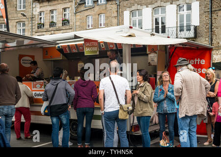 Die Menschen in der Warteschlange für Galette saucisse (gegrillte Würstchen in Krepp umwickelt) im Donnerstag Wochenmarkt in Dinan, Bretagne, Frankreich Stockfoto