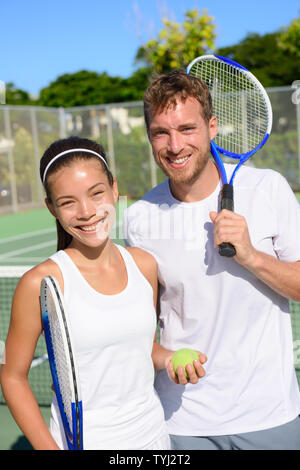Tennis Sport - Mixed paar Spieler Portrait Entspannung nach Spielen im Sommer im Freien. Glücklich lächelnde Menschen auf dem Tennisplatz im Freien, gesunden, aktiven Lebensstil. Frau und Mann Athleten Stockfoto