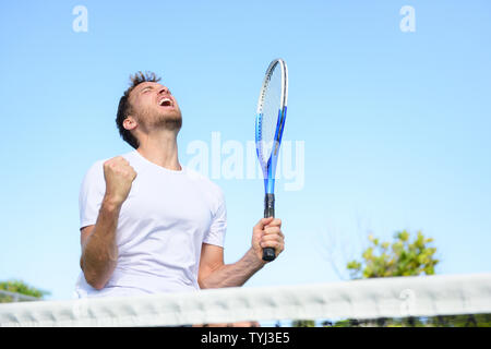 Tennis Player Mann gewinnen Jubel feiern den Sieg. Gewinner der Mensch in der Feier von Erfolg glücklich und gewinnen. Passen männlichen Athleten am Tennisplatz im Freien holding Tennisschläger im Triumph durch das Netz. Stockfoto