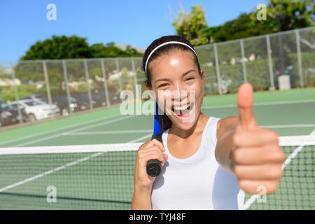 Tennis Player Frau Daumen hoch geben, glücklich und begeistert von der Kamera. Erfolgreiche gewinnen weiblichen Athleten, die gesunden, aktiven Sport Fitness Lebensstil im Freien im Sommer am Tennisplatz. Stockfoto