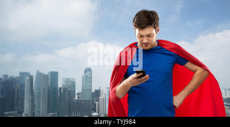 Mann in superhero Cape mit Smartphone über die Stadt Stockfoto