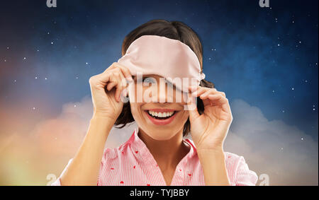 Glückliche junge Frau peeking unter Schlafbrille Stockfoto