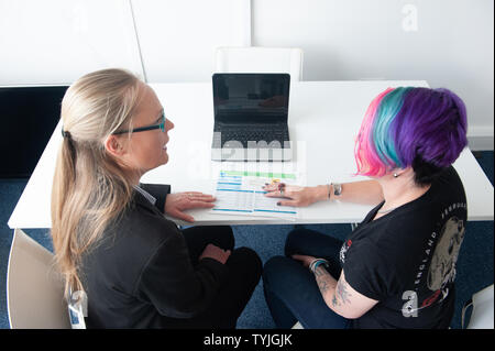Zwei Frauen in der Diskussion um den Papierkram mit Laptop Stockfoto