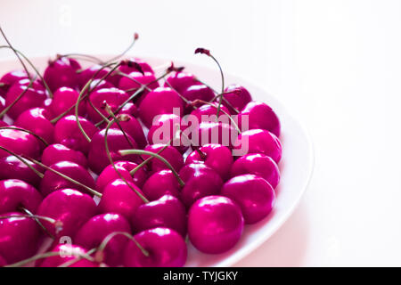 Platte mit süßkirschen Nahaufnahme. Frisch geerntete Sommer Berry in weiße Schüssel. Vitamin mit reifen Früchten. Raw Food Ingredient, vegetarische Ernährung Komponente. Pink, pop Farbige Stockfoto