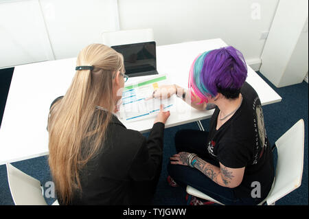 Zwei Frauen in der Diskussion um den Papierkram mit Laptop Stockfoto