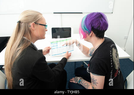 Zwei Frauen in der Diskussion um den Papierkram mit Laptop Stockfoto