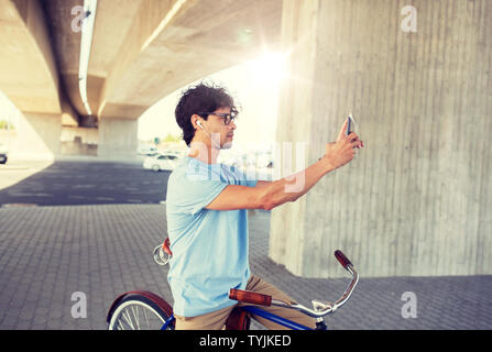 Mann mit Smartphone und Ohrhörer auf dem Fahrrad Stockfoto