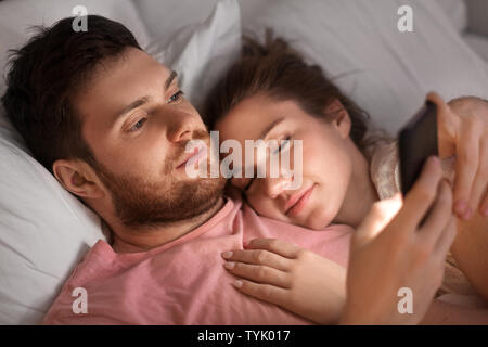 Mann sie ihr Smartphone während Freundin schlafen ist Stockfoto