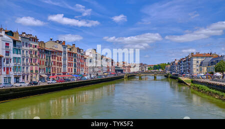 Blick auf typische baskische Architektur auf Häusern entlang des Flusses Nive. Seitenansicht von der Brücke. Bayonne, Frankreich Stockfoto