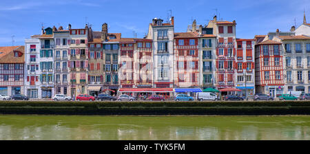 Blick auf typische baskische Architektur auf Häusern entlang des Flusses Nive. Seitenansicht von der Brücke. Bayonne, Frankreich Stockfoto