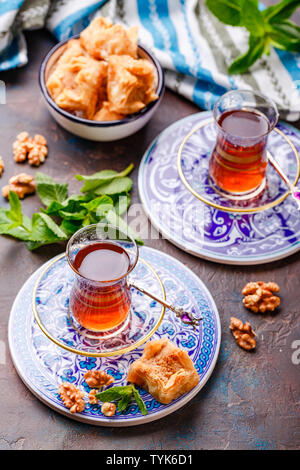 Im Nahen und Mittleren Osten oder arabischen Tee mit Minze in einem traditionellen Glas Schale und Türkische Süßigkeit Baklava. Ramadan Kareem. Eid Mubarak. Islamische Feiertage decorat Stockfoto