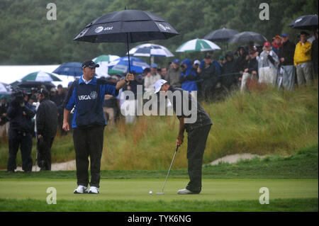 Tiger Woods' caddie Steve Williams hält einen Regenschirm als Holz richtet einen Schlag auf dem 6. grün während der ersten Runde der US-Open am Bethpage Black in Farmingdale, New York am 18. Juni 2009. (UPI Foto/Kevin Dietsch) Stockfoto