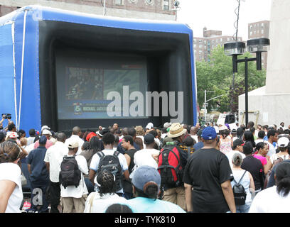 Menschen versammeln sich in Harlem die Michael Jackson memorial Service auf einem riesigen TV-Bildschirm am 7. Juli 2009 in New York City zu sehen. Die landesweit ausgestrahlten Gedenkgottesdienst wird in Los Angeles statt zwei Wochen nach dem pop Sänger starb. (UPI Foto/Monika Graff) Stockfoto