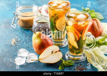 Eis Tee mit Minze und Birne in Glas Tassen auf blauem Hintergrund. Kräutertee Stockfoto