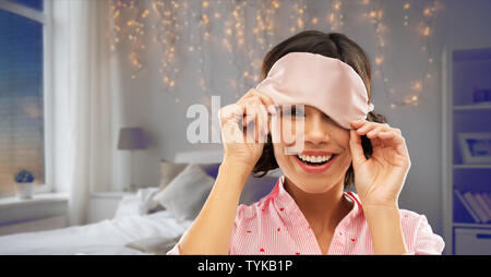 Glückliche junge Frau peeking unter Schlafbrille Stockfoto