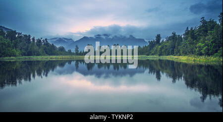 Lake Matheson, in der Nähe der Stadt Fox Gletscher auf der Südinsel Neuseelands ist, ist der Ort für viele Fotografen fotografieren die Reflexion von Cook Snow Mountain. Leider sind die aufeinander folgenden starken Regen völlig Der aufnahmeplan gestört. Wenn der Regen wird kleiner, rund um den See für eine Woche, die Luft ist noch ziemlich frisch. Der Regen und Nebel vollständig abgeschirmt der Koch Schnee in den Bergen, und die Sonne etwas Licht in die dicken Wolken schien. Stockfoto