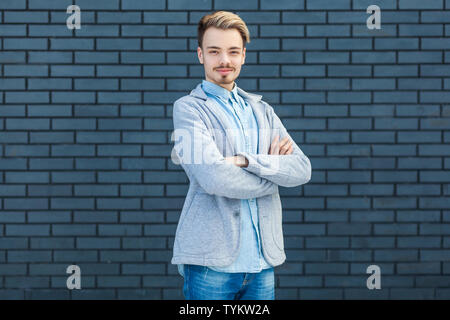 Portrait von glücklich Erfolgreiche hübscher junger blonder Mann in lässigen Stil stand mit verschränkten Armen und Kamera mit Lächeln und Glück. indo Stockfoto