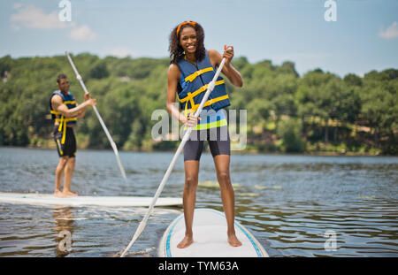 Porträt eines lächelnden jungen Paar Spaß paddleboarding. Stockfoto