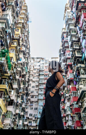 Frau vor Hochhaus mit vielen Einheiten in Hongkong Stockfoto