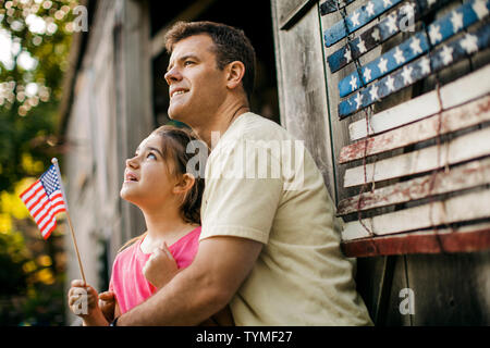 Gerne Vater und Tochter stand vor einer amerikanischen Flagge. Stockfoto