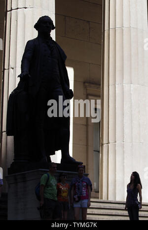 Die Menschen sammeln sich um eine Statue des ersten Präsidenten der Vereinigten Staaten, George Washington, vor der Federal Hall National Memorial, die von der New Yorker Börse vor dem schließenden Glocke an der Wall Street in New York City am 17. August 2011. UPI/John angelillo Stockfoto