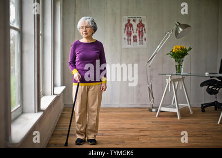 Ältere Frau schaut aus dem Fenster in einer Arztpraxis. Stockfoto