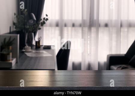 Leer aus Holz Tisch auf die Unschärfe der Vorhang Fenster und Schreibwaren Schreibtisch mit Sonnenlicht am Morgen. Kann als Mock up oder kopieren Sie Raum für Produkt p verwendet werden. Stockfoto