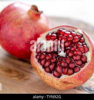 Granatapfelbaum schneiden Sie Samen Nahaufnahme mit geringer Tiefenschärfe auf Holz Schneidebrett zu zeigen Stockfoto