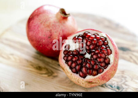 Granatapfelbaum schneiden Sie Samen Nahaufnahme mit geringer Tiefenschärfe auf Holz Schneidebrett zu zeigen Stockfoto